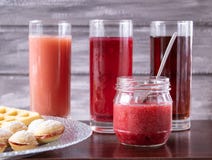 Suco vermelho em um vidro ao lado de uma bacia de cookies e de um frasco pequeno do doce imagens de stock royalty free Suco vermelho em um vidro ao lado de uma bacia de cookies e de um frasco pequeno do doce imagens de stock royalty free