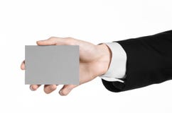 Sujet d'affaires et de publicité : Homme dans le costume noir jugeant un disponible gris de carte vierge d'isolement sur le fond Photos libres de droits Sujet d'affaires et de publicité : Homme dans le costume noir jugeant un disponible gris de carte vierge d'isolement sur le fond Photos libres de droits