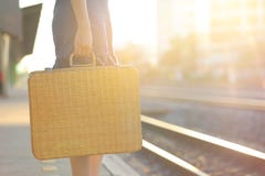 Summer vacation concept, Closeup of woman holding brown natural wicker bag at train station on evening sunset light, Fashionable royalty free stock image Summer vacation concept, Closeup of woman holding brown natural wicker bag at train station on evening sunset light, Fashionable royalty free stock image