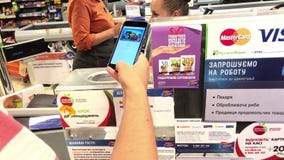 SUMY, UKRAINE - AUG 13, 2018: Customer paying with apple pay by mobile phone on terminal.