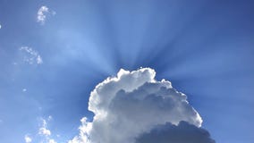 Sun ray shine through white fluffy cloud on bright sunny day with blue sky