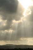 Sun shines through a cloudy sky over the mountains stock image Sun shines through a cloudy sky over the mountains stock image