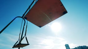 Sunlit playground swings swaying with nobody on them