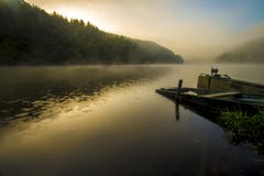 Old looking small boat on an lake at sunrise time with fog royalty free stock images Old looking small boat on an lake at sunrise time with fog royalty free stock images