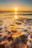 Sunrise over beach with shoreline waves.