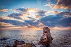 Sunrise over a rocky beach. Colorful clouds reflecting in the sea stock image Sunrise over a rocky beach. Colorful clouds reflecting in the sea stock image