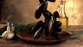 Super slow motion mussels fall into a wooden plate on the table. Filmed on a high-speed camera at 1000 fps.