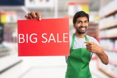 Supermarktangestellter, der großes Verkaufspapier hält lizenzfreie stockfotografie Supermarktangestellter, der großes Verkaufspapier hält lizenzfreie stockfotografie