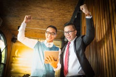 Supporto dell'uomo d'affari di due asiatici ed esaminare compressa, essi allegri e celebrati il suo riuscito nella missione immagine stock Supporto dell'uomo d'affari di due asiatici ed esaminare compressa, essi allegri e celebrati il suo riuscito nella missione immagine stock