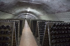 Supports avec des bouteilles de vin mousseux dans le sous-sol dans un établissement vinicole image stock Supports avec des bouteilles de vin mousseux dans le sous-sol dans un établissement vinicole image stock