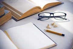 Sur la table sont les encyclopédies, le journal intime, les verres, le crayon et les copeaux photo libre de droits Sur la table sont les encyclopédies, le journal intime, les verres, le crayon et les copeaux photo libre de droits