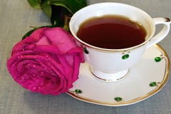 Sur la table étendue une rose, se tenant à côté d'une tasse de porcelaine avec le thé image stock Sur la table étendue une rose, se tenant à côté d'une tasse de porcelaine avec le thé image stock