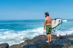 A surfer stands on the rocks royalty free stock images A surfer stands on the rocks royalty free stock images