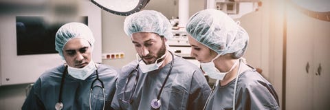 Surgeons discussing over digital tablet in operation room royalty free stock images Surgeons discussing over digital tablet in operation room royalty free stock images