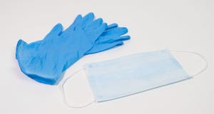 Surgical face mask and blue nitrile gloves on white table. PPE for virus prevention.