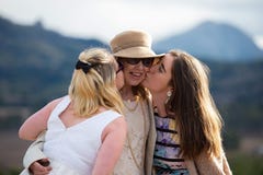 Surprise kisses for Mother of Bride from daughter and bridesmaid