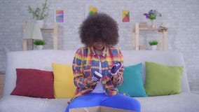 Surprised and upset african american woman with an afro hairstyle unpacks the parcel,wrong size stock video Surprised and upset african american woman with an afro hairstyle unpacks the parcel,wrong size stock video
