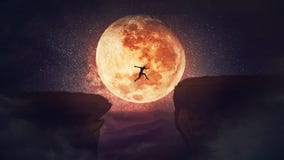 Surreal scene, self overcome concept, as determined man jump over a chasm obstacle. Way to win and success over starry night with