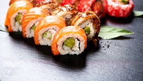 Sushi Rolls Closeup. Japanese Food In Restaurant. Roll With Salmon, Eel, Vegetables And Flying Fish Caviar Royalty Free Stock Images