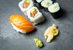Sushi and Sashimi rolls on a black stone slatter. Fresh made Sushi set with salmon, prawns, wasabi and ginger. Traditional Japanes Royalty Free Stock Photography Sushi and Sashimi rolls on a black stone slatter. Fresh made Sushi set with salmon, prawns, wasabi and ginger. Traditional Japanes Royalty Free Stock Photography