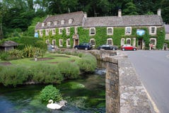 Svanar på floden Coln framme av svanhotellet, Bibury, England royaltyfria foton Svanar på floden Coln framme av svanhotellet, Bibury, England royaltyfria foton