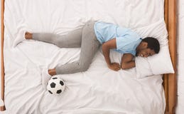 Svart idrottsman med bollen som sover på säng royaltyfri fotografi Svart idrottsman med bollen som sover på säng royaltyfri fotografi