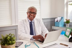 Svart manlig doktor för pensionär på ett kontorsskrivbord som ser till kameran royaltyfri bild Svart manlig doktor för pensionär på ett kontorsskrivbord som ser till kameran royaltyfri bild