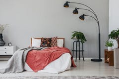Svart stilfull lampa i det eleganta sovrummet som är inre med den bekväma dubbelsäng, växter och nattduksbordet arkivbild Svart stilfull lampa i det eleganta sovrummet som är inre med den bekväma dubbelsäng, växter och nattduksbordet arkivbild