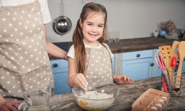 A sweet daughter mixes eggs and flour in a bowl. The girl is going to do the mafina with her mother stock images A sweet daughter mixes eggs and flour in a bowl. The girl is going to do the mafina with her mother stock images
