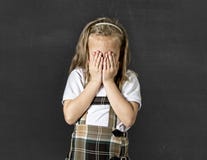 Sweet junior schoolgirl with blonde hair crying sad and shy in front of school class blackboard stock photo Sweet junior schoolgirl with blonde hair crying sad and shy in front of school class blackboard stock photo