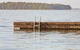 Swimming dock with ladder on a beautiful calm blue lake stock photography Swimming dock with ladder on a beautiful calm blue lake stock photography