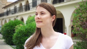 swobodny ruch Uśmiechnięta młoda kobieta w białej koszulka spaceru puszka ulicie w europejskim mieście Patrzeć Wokoło zbiory wideo swobodny ruch Uśmiechnięta młoda kobieta w białej koszulka spaceru puszka ulicie w europejskim mieście Patrzeć Wokoło zbiory wideo