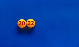 Symbol of the new year 2022. Orange table tennis balls with the number `2022` on a beautiful blue background, copy space. Busine