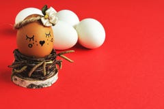 Self-centered light brown egg with satin flower in bed tones in nest of birch twigs and white eggs on bright red background. Minim stock photo Self-centered light brown egg with satin flower in bed tones in nest of birch twigs and white eggs on bright red background. Minim stock photo