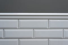 Szarość malująca ściana, część ściana jest zakrywającym płytki małym białym glansowanym cegłą, ceramiczne dekoracyjne formierstwo zdjęcia stock Szarość malująca ściana, część ściana jest zakrywającym płytki małym białym glansowanym cegłą, ceramiczne dekoracyjne formierstwo zdjęcia stock