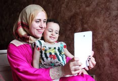 Szczęśliwa arabska muzułmańska matka z jej dziewczynką bierze selfie obrazy royalty free Szczęśliwa arabska muzułmańska matka z jej dziewczynką bierze selfie obrazy royalty free