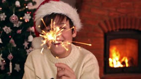 Szczęśliwa chłopiec jest ubranym Santa kapelusz i trzyma bożego narodzenia sparkler zbiory wideo Szczęśliwa chłopiec jest ubranym Santa kapelusz i trzyma bożego narodzenia sparkler zbiory wideo