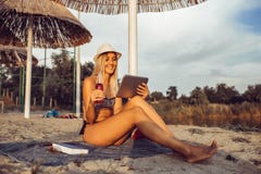 Szczęśliwa dziewczyna używa pastylkę na plaży zdjęcie stock Szczęśliwa dziewczyna używa pastylkę na plaży zdjęcie stock