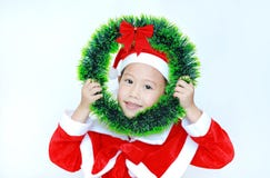 Szczęśliwa małe dziecko dziewczyna w Santa kostiumu z mienia round Bożenarodzeniowym wiankiem na jej twarzy na białym tle Wesoło zdjęcia royalty free Szczęśliwa małe dziecko dziewczyna w Santa kostiumu z mienia round Bożenarodzeniowym wiankiem na jej twarzy na białym tle Wesoło zdjęcia royalty free