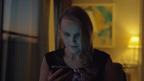 Szczęśliwa młoda kobieta z komórką w wieczór w domu zbiory wideo Szczęśliwa młoda kobieta z komórką w wieczór w domu zbiory wideo