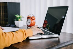 Szczęśliwa przypadkowa młoda azjatykcia kobieta pracuje w domowym, małym biurze z używać lub donosi na biurku jako freelancer obraz stock Szczęśliwa przypadkowa młoda azjatykcia kobieta pracuje w domowym, małym biurze z używać lub donosi na biurku jako freelancer obraz stock
