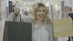 Szczęśliwa z podnieceniem nastoletnia blondynki dziewczyna uśmiecha się jej torba na zakupy i pokazuje kamera w centrum handlowym zbiory wideo Szczęśliwa z podnieceniem nastoletnia blondynki dziewczyna uśmiecha się jej torba na zakupy i pokazuje kamera w centrum handlowym zbiory wideo