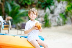 Szczęśliwa śmieszna mała preschool dzieciaka chłopiec pije kokosowego sok na ocean plaży dziecko bawić się na rodzinnych wakacjac obrazy stock Szczęśliwa śmieszna mała preschool dzieciaka chłopiec pije kokosowego sok na ocean plaży dziecko bawić się na rodzinnych wakacjac obrazy stock