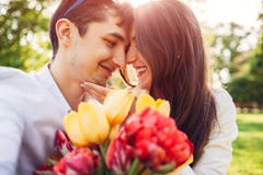 Szczęśliwi potomstwa dobierają się w miłości ściska z wiosna kwiatu bukietem outdoors Mężczyzna obdarzony jego dziewczyna z tulip obrazy royalty free Szczęśliwi potomstwa dobierają się w miłości ściska z wiosna kwiatu bukietem outdoors Mężczyzna obdarzony jego dziewczyna z tulip obrazy royalty free