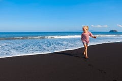 Szczęśliwy bosy dzieciak zabawę na spacerze czerni plażą zdjęcie stock Szczęśliwy bosy dzieciak zabawę na spacerze czerni plażą zdjęcie stock