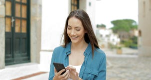 Szczęśliwy kobiety odprowadzenie i wyszukiwać telefon komórkowy w ulicie zbiory Szczęśliwy kobiety odprowadzenie i wyszukiwać telefon komórkowy w ulicie zbiory