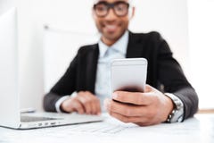 Szczęśliwy młody biznesmen używa telefon komórkowego podczas gdy pracujący Obrazy Stock Szczęśliwy młody biznesmen używa telefon komórkowego podczas gdy pracujący Obrazy Stock