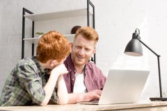szczęśliwy ojciec i syn uśmiecha się each inny podczas gdy używać laptop wpólnie obrazy stock szczęśliwy ojciec i syn uśmiecha się each inny podczas gdy używać laptop wpólnie obrazy stock