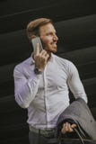 Szczęśliwy uśmiechnięty miastowy biznesmen używa mądrze telefon outside zdjęcia stock Szczęśliwy uśmiechnięty miastowy biznesmen używa mądrze telefon outside zdjęcia stock