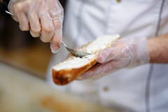 Szef kuchni przygotowywa baguette z łososiem, ręki w polietylen rękawiczkach obrazy stock Szef kuchni przygotowywa baguette z łososiem, ręki w polietylen rękawiczkach obrazy stock
